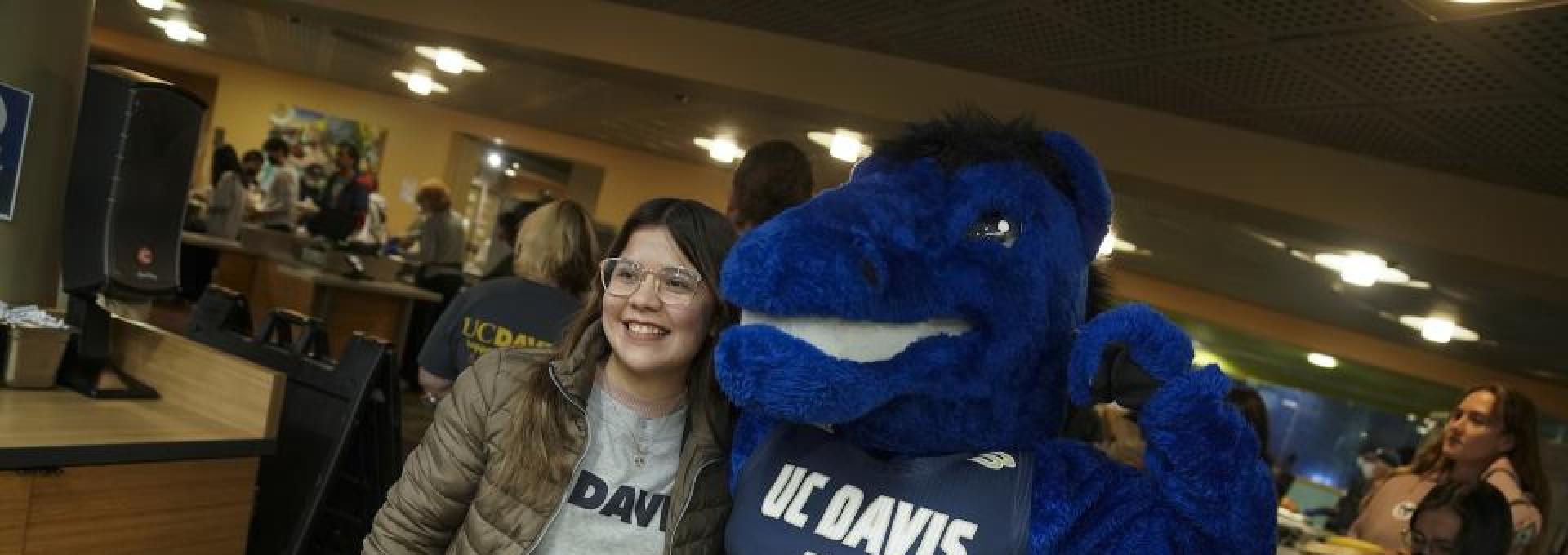 Person standing next to a flexing Gunrock mascot