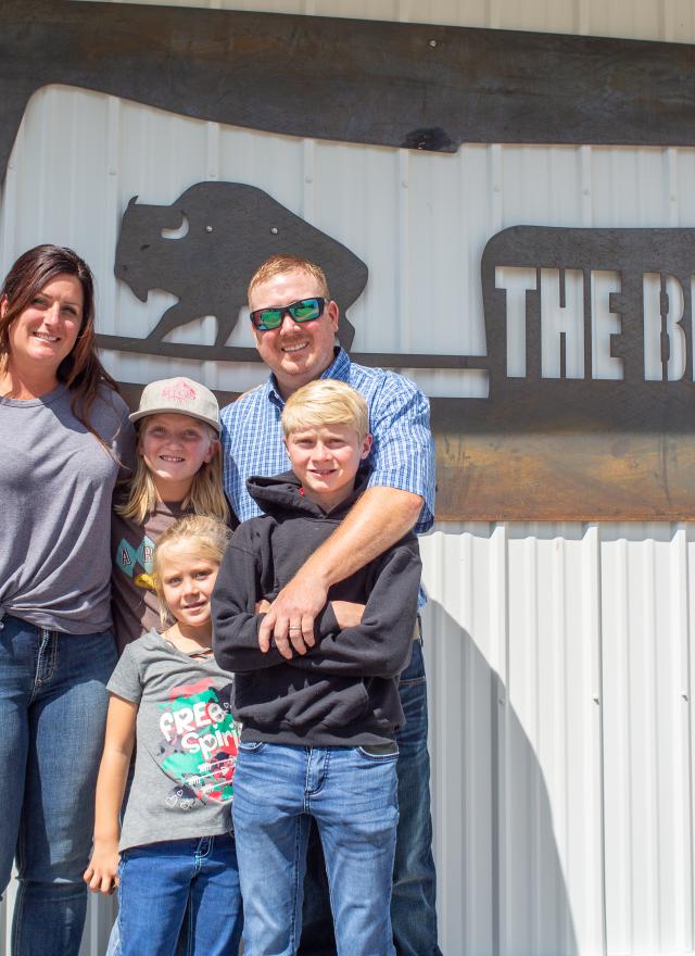 Williams family posing in front of their business sign