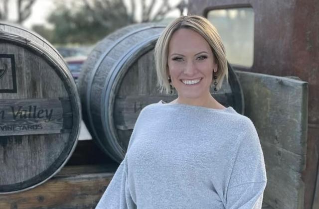 Natalie Frazier in front of wine barrels