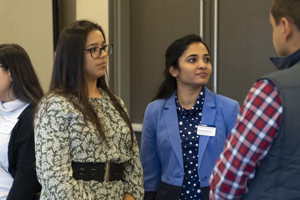 Deepi Agarwal and Fernanda Castro Villegas listening to an executive