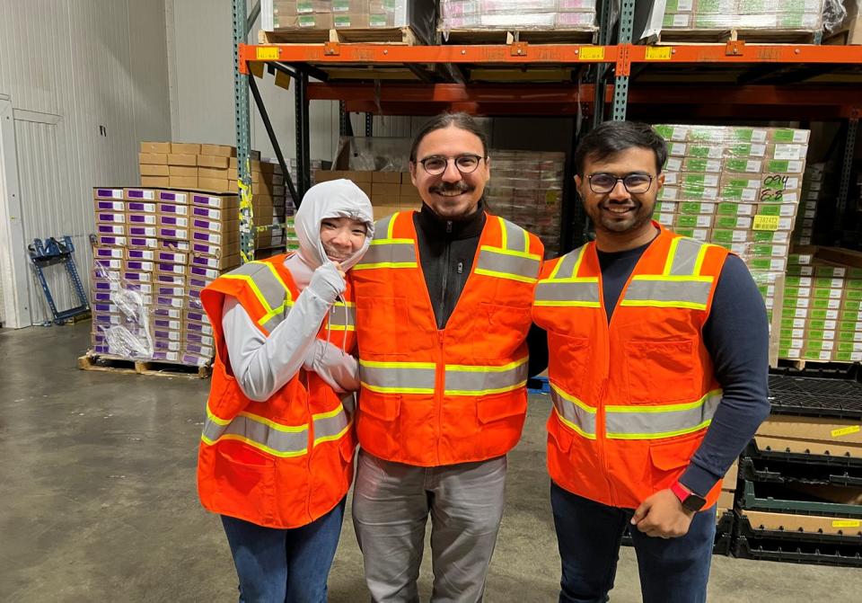 Sayar Banner Banerjee and two other students wearing safety vest at a warehouse