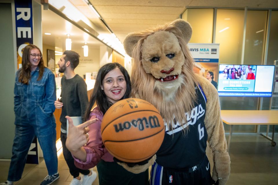 MBA student points to basketball held by Sacramento Kings Mascot Slamson