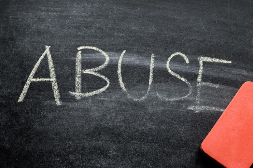 Abuse written in chalk on a black chalk board