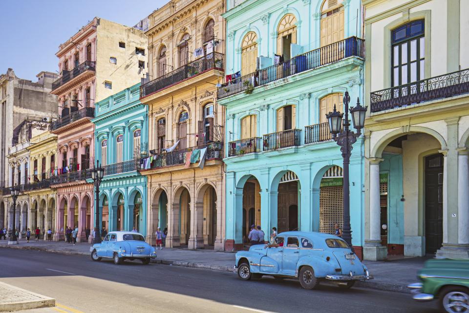 Vintage cars parked on roadside. Taxis on street in city. Vehicles against residential buildings.