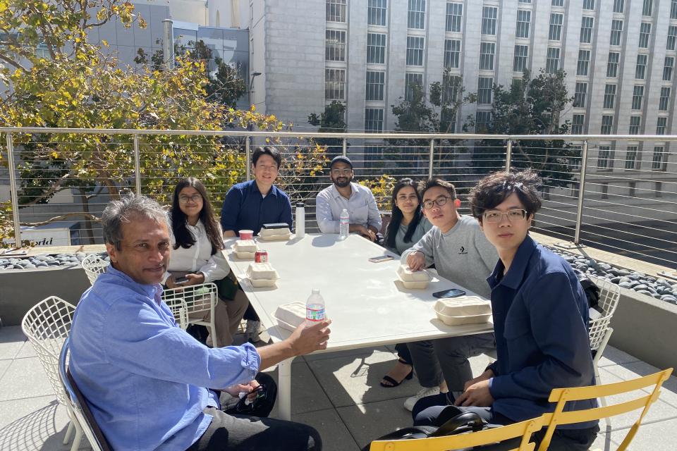 people sitting around a table outside enjoying drinks and food