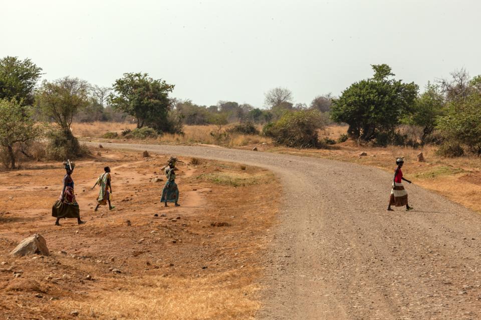 African village women escaping from the camera, They are laughing and They are carrying baskets - motion.