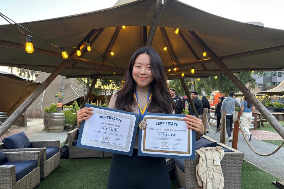 Yuna Kim holding up two certificates