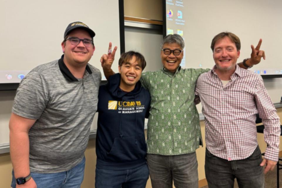 Timothy O'Brien, Alex Schultz, and Kyle Wong, and Lecturer Marc Lowe in a classroom